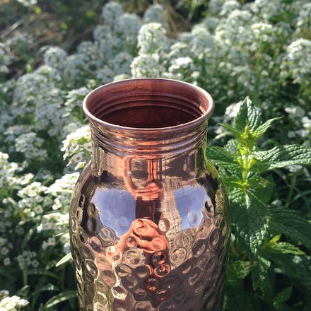 Copper water bottle with white flowers in the background