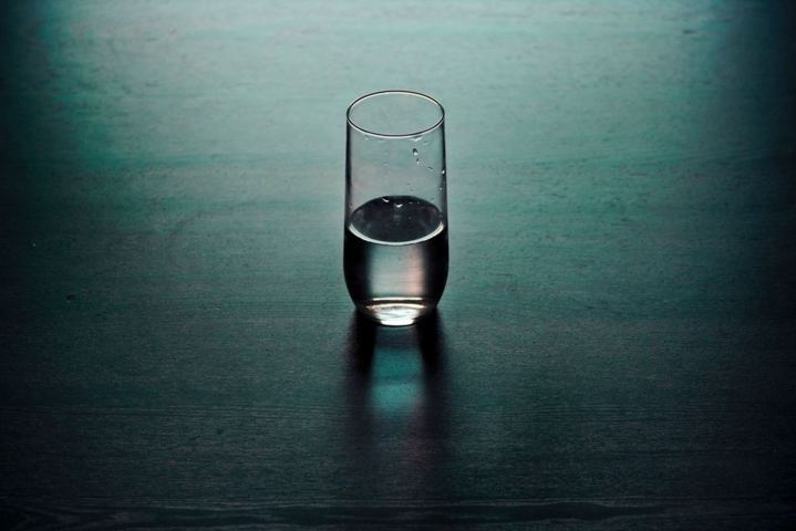 glass of water on a wooden surface dark background