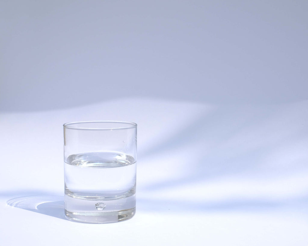 one glass filled with water placed on the side white background
