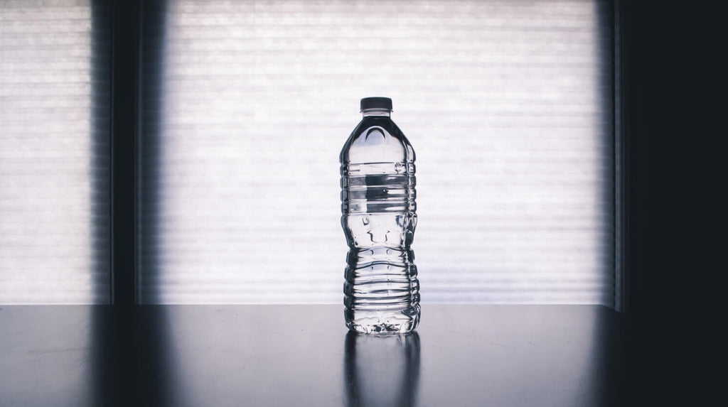 clear plastic disposable bottle filled with water placed on dark table