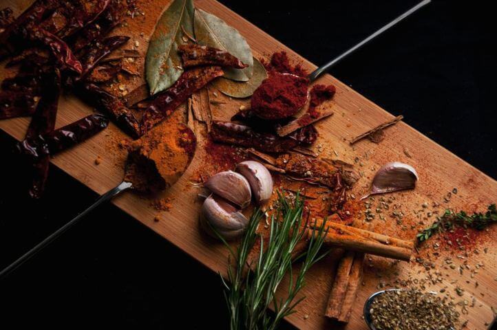 different types of spices herbs and garlic placed on wooden board